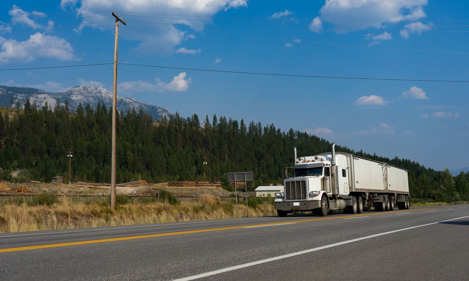 White tractor-trailer rolling down a mountain highway on a clear day