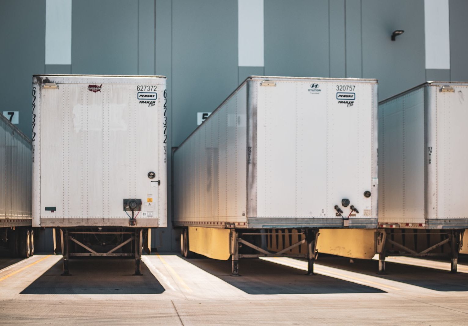 Dry-van trailers backed to a loading dock, sealed and tagged