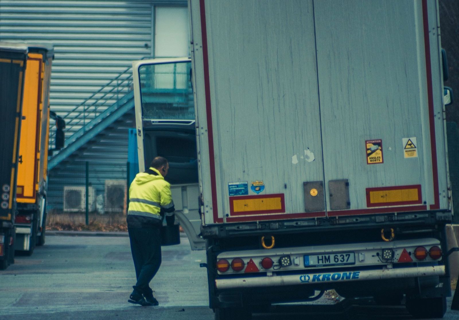 Driver in hi-vis opening trailer doors at a receiving dock